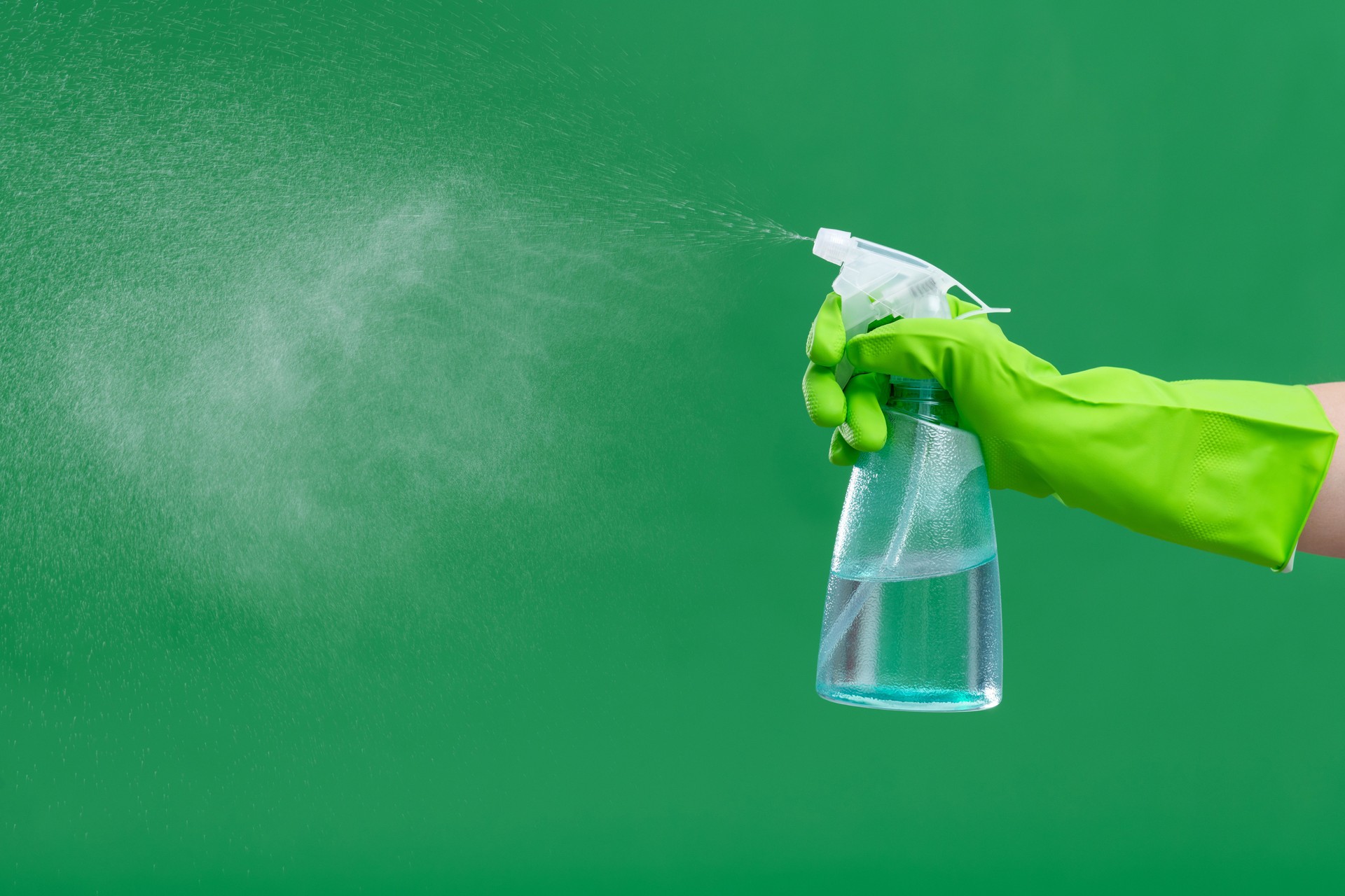 Hand using spray bottle on green background